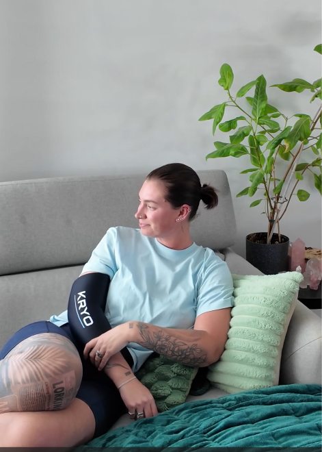 Female athlete wearing the KRYO FLEX ice compression sleeve for targeted cold compression and post-workout recovery of the elbows, ankles and arms.