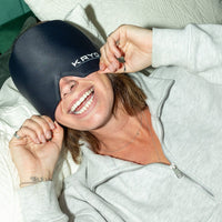 Woman smiling while wearing the KRYO Head Ice Cap at home, demonstrating a wearable hot and cold gel cooling cap for head cooling, comfort and relaxation.