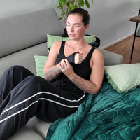 Female athlete relaxing on a couch while wearing the KRYO Wrist Ice Compression Sleeve for targeted cold compression and post-workout wrist recovery.