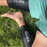 Runner wearing KRYO CORE and MAX ice compression sleeves outdoors for post-run recovery