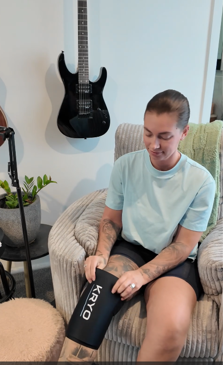 Female athlete demonstrating the KRYO CORE ice compression sleeve for targeted cold compression and post-workout recovery of the knees and calves. 