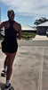Woman running outdoors and using a KRYO CORE cold compression sleeve on her knee for post-run recovery.