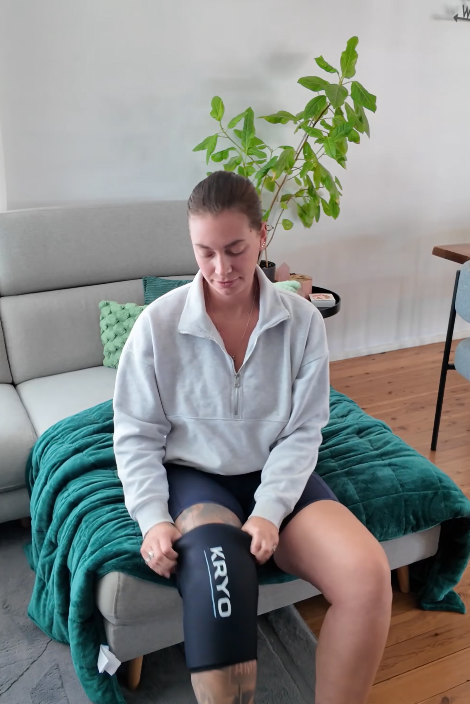 Female athlete demonstrating the KRYO MAX ice compression sleeve for targeted cold compression and post-workout recovery of the thighs, quads and hamstrings. 